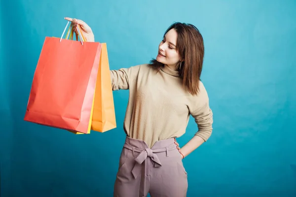 Image of happy young girl standing on blue background with shopping bags — Stock Photo, Image