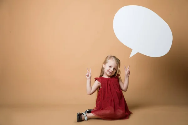 Fille s'asseoir sur le sol sur un fond orange. La fille est très heureuse. De la fille suspendue blanc blanc discours — Photo