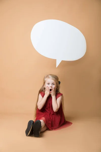 Fille s'asseoir sur le sol sur un fond orange. La fille est très heureuse. De la fille suspendue blanc blanc discours — Photo