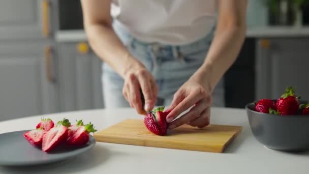 Flickan klipper jordgubbar i ett ljust kök. Hälsosam mat — Stockvideo