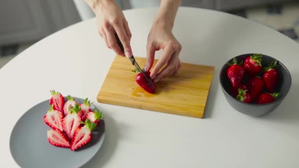 Flickan klipper jordgubbar i ett ljust kök. Hälsosam mat — Stockvideo