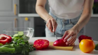 Kız parlak bir mutfakta sebze kesiyor. Sağlıklı yemek..