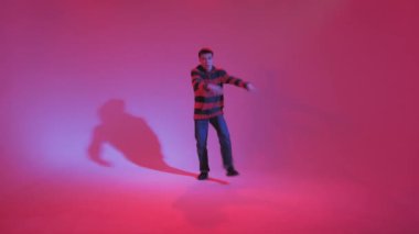 Jumperlı Genç Adam Stüdyoda Çağdaş Dans Ediyor. Breakdance. Dans okulu posteri. Uzayı kopyala Savaş yarışması duyurusu. Pembe ve Mavi Arkaplan.