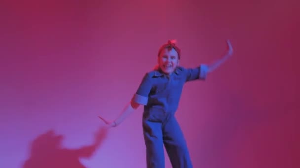 Mladá stylová dívka tančí v ateliéru na barevném neonovém pozadí. Design plakátu Music DJ. — Stock video