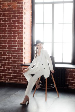 Beyaz takım elbiseli ve siyah şapkalı genç kız. Giysi konsepti.