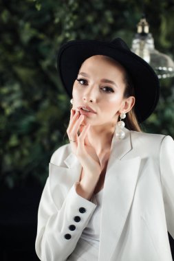 Beyaz takım elbiseli ve siyah şapkalı genç kız. Giysi konsepti.