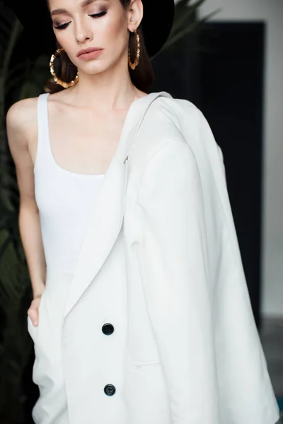 Chica joven con un traje blanco y un sombrero negro. El concepto de ropa . — Foto de Stock