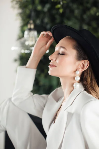 Chica joven con un traje blanco y un sombrero negro. El concepto de ropa . — Foto de Stock