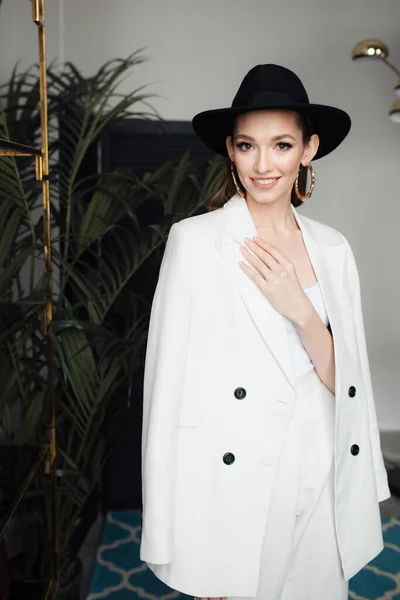 Chica joven con un traje blanco y un sombrero negro. El concepto de ropa . — Foto de Stock