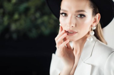 Beyaz takım elbiseli ve siyah şapkalı genç kız. Giysi konsepti.