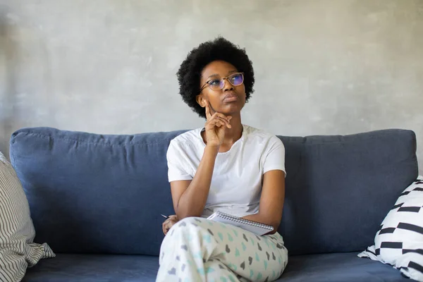 African American girl writes in a notebook in a cozy room — Stock Photo, Image