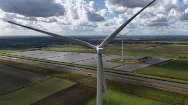Rüzgar türbinleri ve güneş panelleri 60 fps, temiz enerji, yenilenme enerjisi. Sürdürülebilir enerji üretimi. Groningen, Hollanda. Hava görünümü.