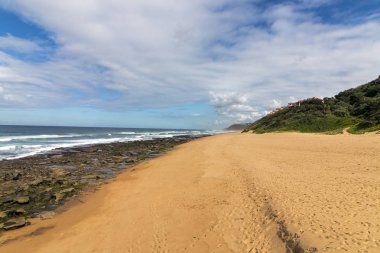 Düşük tide kayalık plaj dalgalar ve okyanus mavi bulutlu gökyüzü deniz manzarası Garvies Beach, karşı blöf, Durban, Güney Afrika