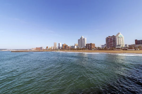 Ocean and beach against Golden Mile coastal city skyline and blue sky in Durban, South Africa