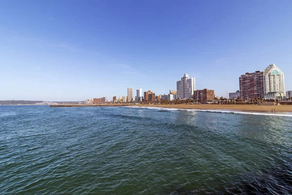Ocean and beach against Golden Mile coastal city skyline and blue sky in Durban, South Africa
