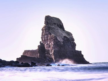 Deniz yığın siluet günbatımı gökyüzü tarafından keskin. Akşam ışığı taşlar, kayalar ve uçurumun yüz Talisker Bay, Isle of Skye
