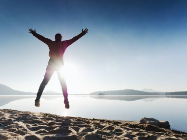 Güzel bir gün batımı zemin karşı sahilde koşan adam. Kum derin ayak izleri ile dağ gölü.