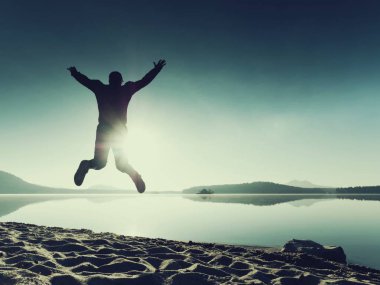 Güzel bir gün batımı zemin karşı sahilde koşan adam. Kum derin ayak izleri ile dağ gölü.