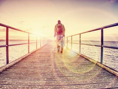 Gezgin bandaj yaralı bacak ile Deniz Köprüsü üzerinde kal. Kırık bacak koltuk değneği ile turist. Kırık bacak adamla tam uzunlukta.