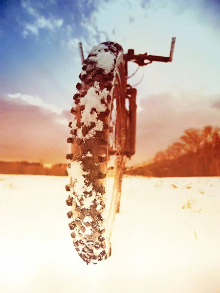 Abstract effect. Front bike detail on a winter trail, path covered by snow. Sportive backgrounds and still-life. Biking in the countryside.