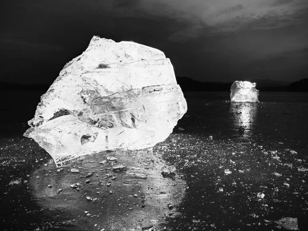 Ice with reflection on the lake. Crushed ice floe on reflective natural background.  Natural iceberg with depth of field.  Black and white photo.