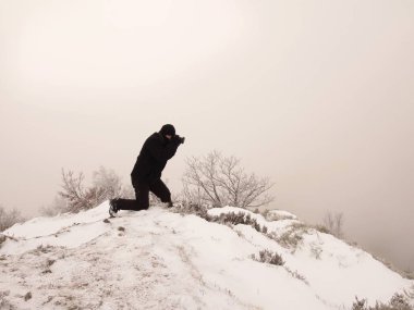 Manzara fotoğraf yapmak karlı kayada kameralı adam. Karlı ve puslu arka plan fotoğrafçı. Tehlikeli hava