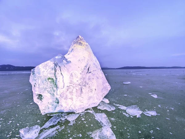 Ice floe and crushed ice on dark frozen and flat  ground. Shining crushed ice in strong colorful backlight.