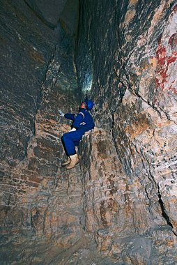 Workerman kask ve koruyucu elbise glowes ve kafa lambası kullanarak. Adam eski maden havalandırma boşluğunda iş. Yeraltı işçi. 