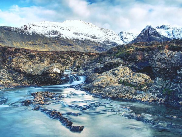 Blue water of river Brittle in trail known as Fairy pools. The mountain river cut in soft rocks colorful pools.  Bellow the mountains of Glenbrittle on Isle of Skye Scotland