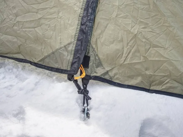 Detail of camping tent anchored in snow. Extreme winter trek. Aluminum Tent Poles and rainfly.