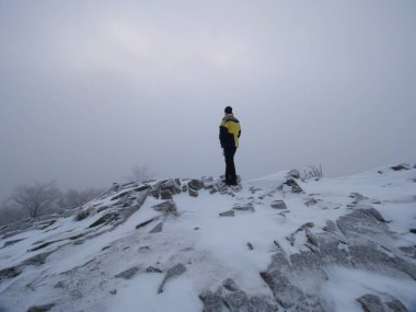 Kış puslu manzara. Turist sıcak giysiler ile dondurulmuş kayalık tepe üzerinde yoğun bir sis evde. Milli Parkı. 