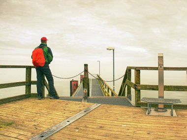 Deniz ahşap iskele üzerinde arkadan görünüşü turist trekking giysili. Degrade puslu görünümü