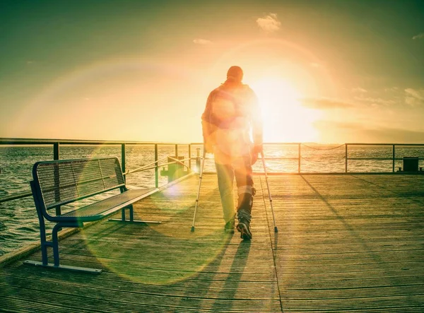 無効けがハイカーの男性は彼のターゲットの一人で添付ファイルを祝うため 観光客がスタンドや空が海の水に触れる暖かい夕日 水平線内海橋の上歩く — ストック写真