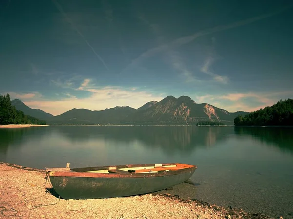 ボートは アルプスの湖の銀行に固定されています 山は青い湖の滑らかな水のレベルでミラー化します ドラマチックで美しいシーン — ストック写真