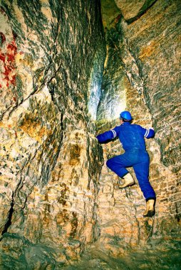 Karanlık eski tüneli, kapalı ateş adam. Turuncu kum taş duvarlar ile tünel merdivenlere. Mavi genel ve güvenlik kask içinde personel.