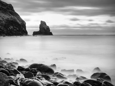 Rüzgarsız denizde akşam içinde mavi bir atmosfer. Pürüzsüz denizden çıkmış büyük yuvarlak kayalar.