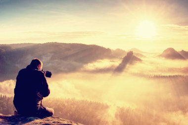 Adam uzun yürüyüşe çıkan kimse konaklama Dslr fotoğraf makinesi ile fotoğraf çekmek için dağın zirvesinde. Güzel misty Vadisi ve renkli alçak bulutlar