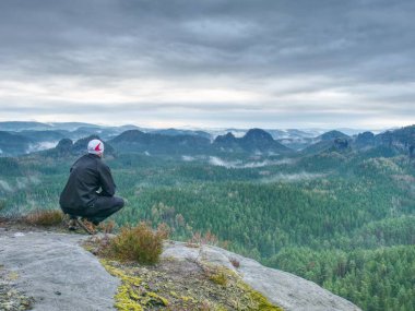 Dağ uzun yürüyüşe çıkan kimse huysuz puslu peyzaj arıyorum. Bir dağın tepesinde adam arkadan görünüş.