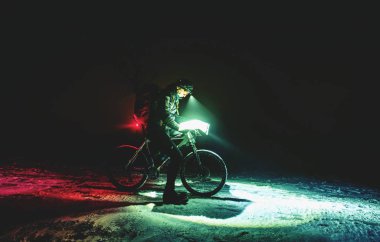 Kış gece mtb yarışı rakip possition denetimi için durdurmak. Gece kar yağışı sırasında harita içine bakarak beyaz şişman bisikleti ile motorcu. 