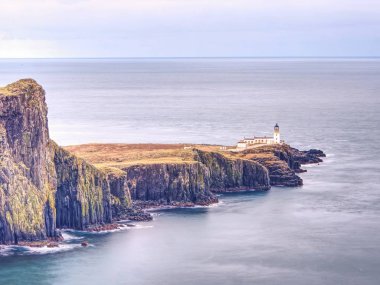 Neist noktası Yarımadası ile deniz feneri, turizm Isle of Skye, İskoçya üzerinde. Köpüklü mavi deniz keskin uçurum karşı grev. Tüm yolcuları görmek gerekir