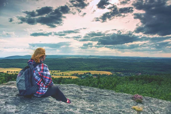 Genç kız turist uçurumun kenarında oturur ve Dağları'nın eteklerinde orman bakar. Rüzgarlı bir gün ile clounds arasında gizli güneş. 