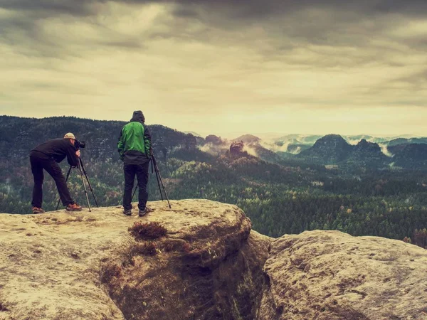 Photographer is taking a picture of landscape . Two men hiking and taking pictures. Camp, adventure, trip and traveling concept.