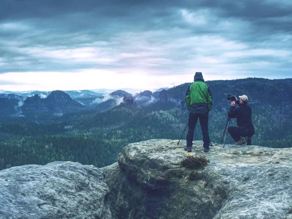 Photographer is taking a picture of landscape . Two men hiking and taking pictures. Camp, adventure, trip and traveling concept.