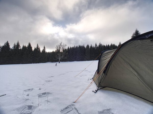 Trekking tent built  against the snowy landscape. Winter skialpinism trek over snowy mountain peaks.