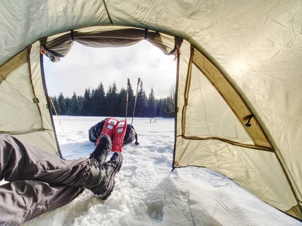 Kış ormandaki çadırda kamp. Dağlarda kar ayakkabıları trek karda bir çadır kurma.