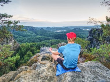 Adam dağlarda vahşi doğa üzerinde yoga konumda günbatımında derin derin düşünür. Meditasyon, maneviyat ve ruh denge kavramı