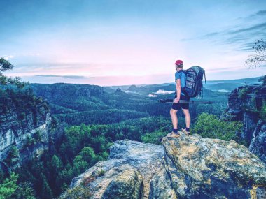 Tripod üzerinde cliff ve düşünme ile profesyonel fotoğrafçı. Rüya gibi manzara gündoğumu içinde. Güzel saf doğa aşağıdaki