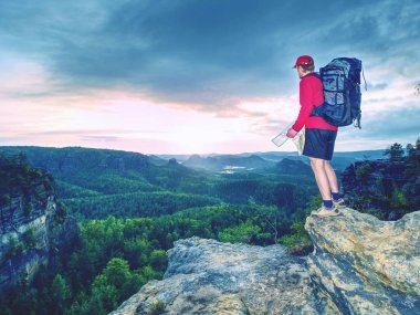 Kağıt harita doğada yürüyüş sırasında arayan genç turist rehberi silüeti. Runner izinde. 