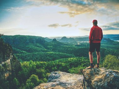 Başarı adam bir zirvesinde peyzaj gözlemlemek. Genç dağcı veya uzun yürüyüşe çıkan kimse kayalık bir tepe üzerinde uygun