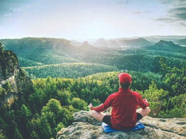 Yoga yapan adam orning içinde kayanın üzerinde poz veriyor. Orta yaşlı sporcu lüks manzaralı dağlarda yoga ve meditasyon yapıyor.